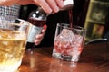 Close up shot of bartender hand pouring drink from measuring cup into a cocktail glass filled with ice cubes. Barman Royalty Free Stock Photo