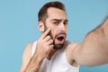 Close up shot bearded young man 20s years old in white shirt doing selfie isolated on blue pastel wall background