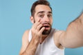 Close up shot bearded young man 20s years old in white shirt doing selfie isolated on blue pastel wall background