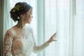 Asian bride standing near window in dressing room Royalty Free Stock Photo