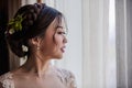 Asian bride standing near window in dressing room Royalty Free Stock Photo