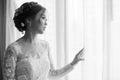 Asian bride standing near window in dressing room Royalty Free Stock Photo