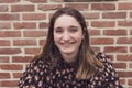 Close Up Shot of a Beautiful brown Haired Teenager smiling, against a red brick background with copy space Royalty Free Stock Photo