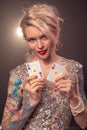 Blonde woman with a beautiful hairstyle and perfect make-up is posing with playing cards in her hands. Casino, poker. Royalty Free Stock Photo