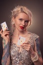 Blonde woman with a beautiful hairstyle and perfect make-up is posing with playing cards in her hands. Casino, poker. Royalty Free Stock Photo