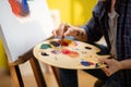 A close up shot of a beautiful woman with shirt hair squeezing out paint onto her palette and she seems quite happy as Royalty Free Stock Photo