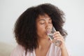 Close-up shot of a black woman drinking still water. Hydrate desire, maintain water balance