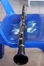 Close-up shot of a black wooden clarinet on a plastic chair.