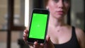 Close-up shot of blurred sportsgirl holding smartphone with chromakey green screen in gym.