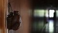 In the close up, shot, brown leather boxing gloves hang on a cord from a rusty nail on a door frame. In the background