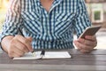 Close up shot business man taking down note writing with ballpoint pen holding, using mobile smart phone in other hand working in