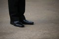 Close-up shot of a business man wearing slacks and black leather shoes standing on a cement floor, outdoor street, optional focus. Royalty Free Stock Photo