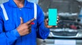 close up shot of car mechanic showing green screen mobile phone by pointing finger at garage - concept of online booking Royalty Free Stock Photo