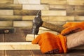 Close-up shot of a carpenter in orange work gloves hammers a nail into a wooden board Royalty Free Stock Photo