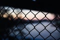 Close-up shot of a chain-link fence with a lake and sunset on the blurred background in Australia Royalty Free Stock Photo