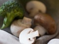 Close-up shot of champignons and a piece of broccoli lying over a kitchen towel