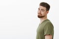 CLose-up shot of charming charismatic bearded boyfriend in t-shirt standing in profile turning head at camera and