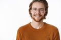 Close-up shot of charming charismatic kind and happy male with beard and glasses in warm sweater smiling broadly at