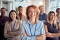 Close-up shot of cheerful female manager and her young team standing in the company building hallway and posing for a photo. Royalty Free Stock Photo