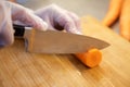 Close up shot of a chef chopping carrots on a wooden chopping board.