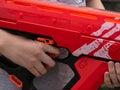 Close up shot of a child holding a red plastic toy blaster