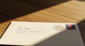 Handwritten First Class Letter Envelope with Postage Stamp on Wooden Table, Illuminated by Dramatic Sunlight Shadow Royalty Free Stock Photo