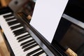 Close-up shot of classical piano and white paper sheet with music notes for performing musical composition.