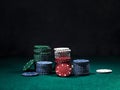 Close-up shot of a colorful chips piles, some of them laying nearby on green cover of playing table. Black background Royalty Free Stock Photo