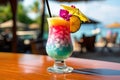 A close-up shot of a colorful tropical cocktail on a beachside bar