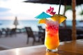 A close-up shot of a colorful tropical cocktail on a beachside bar