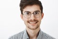 Close-up shot of confident carefree european man with beard and moustache, wearing trendy glasses, smiling broadly and