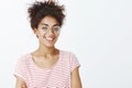 Close-up shot of confident friendly-looking young woman with combed curly hair in trendy glasses and striped t-shirt