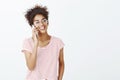 Close-up shot of confident pleased good-looking woman in glasses and striped t-shirt, smiling broadly and gazing right