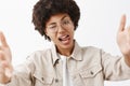 Close-up shot of confident rebel and cool african american lesbian in glasses and beige shirt, showing tongue flirty and