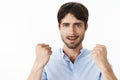 Close-up shot of confident and upbeat young creative handsome man with blue eyes and beard raising clenched fists in yes Royalty Free Stock Photo