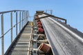 Close-up shot of the conveyor belt in the concrete plant with transport rollers, visible metal stairs and railings. Royalty Free Stock Photo
