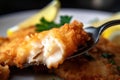 Close-up shot of a crispy fried catfish fillet with visible fork marks, served with a wedge of lemon and a sprig of parsley Royalty Free Stock Photo