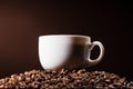 close-up shot of cup standing on heap of coffee beans on dark