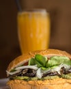 Tasty vegan burger with orange juice in the background