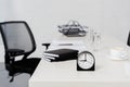 close-up shot of desk with stack of notebooks and alarm clock