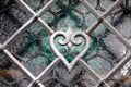 Close-up shot of a detail of a silver wrought iron grill fence with a heart shape in the middle