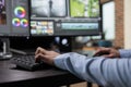 Close up shot of digital video editor sitting at multi monitor workstation desk while working on movie footage. Royalty Free Stock Photo
