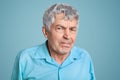 Close up shot of elderly man with wrinkles on face, pressed lips, looks scrupulously and with anger, discontent with something, Royalty Free Stock Photo