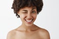 Close-up shot of emotive happy and friendly-looking attractive dark-skinned model with afro hairstyle posing naked