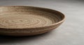 Artisanal Speckled Ceramic Plate with Concentric Rings, Rustic Texture, and Earthy Tones on a Minimalist Grey Surface, Close-up Royalty Free Stock Photo