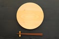 Empty wooden plate with chopsticks on the black table Royalty Free Stock Photo