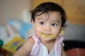 Close up shot of face Asian baby with mouth soiled food after eating, looking out