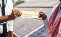 close up shot of farmer receiving check from banker in front of solar panel - concept of financial support for renewable Royalty Free Stock Photo