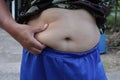 Close-up shot of a fat man holding his hand to his bloated belly Royalty Free Stock Photo