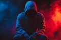 A close-up shot features a hacker wearing a black hood on a dark background Royalty Free Stock Photo